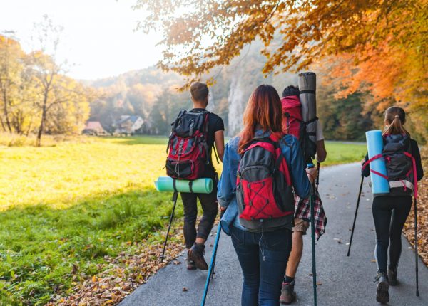 Friends with backpacks walking outdoor together, trekking and tourism